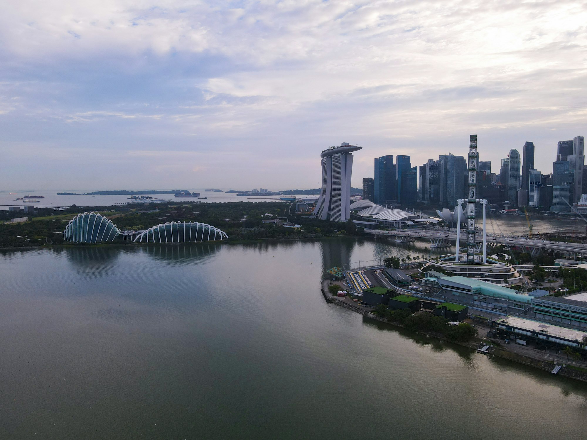 Singapore skyline, Marina Bay Sands and the Gardens by the Bay conservatories beside the water at sunrise.
